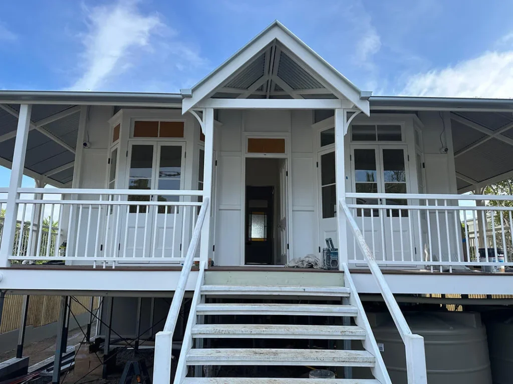 A white house with a porch and stairs, recently repainted, located in Annerley.